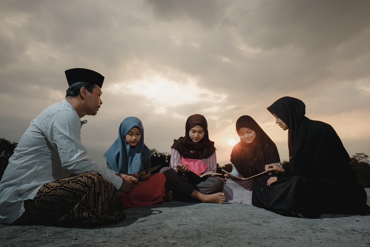 Evening group Quran study session Five people sitting outdoors in a circle reading books during sunset