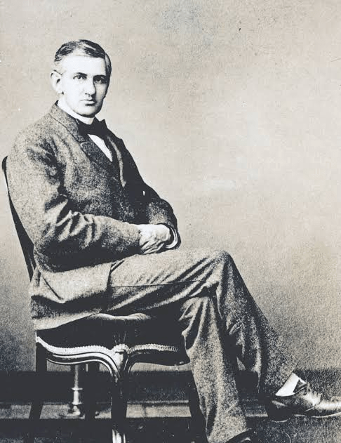 Vintage portrait of a man seated in formal attire, featuring a bow tie and a suit, looking directly at the camera.