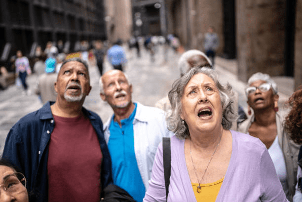 A diverse group of elderly people looking up with expressions of surprise and curiosity in an urban setting.