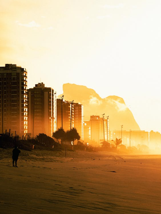 Sunset over urban beach skyline Beachfront cityscape with tall buildings at sunset and a person walking on sand