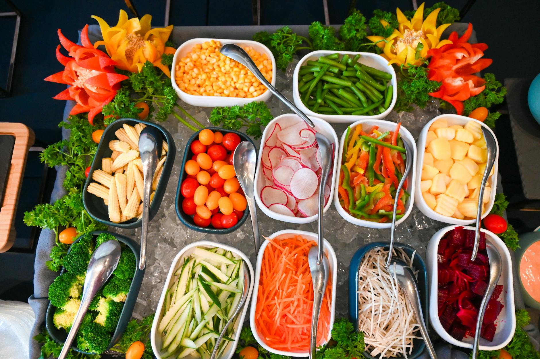 Assorted fresh vegetables in individual bowls at a salad bar buffet, displayed on ice.