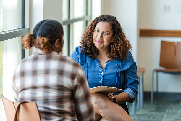 A counselor attentively listening to a person during a one-on-one session in a bright room