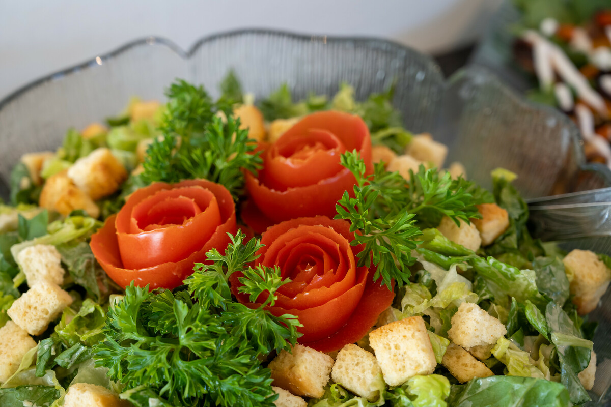 Fresh garden salad with tomato roses garnish Salad with lettuce, parsley sprigs, croutons, and tomato roses