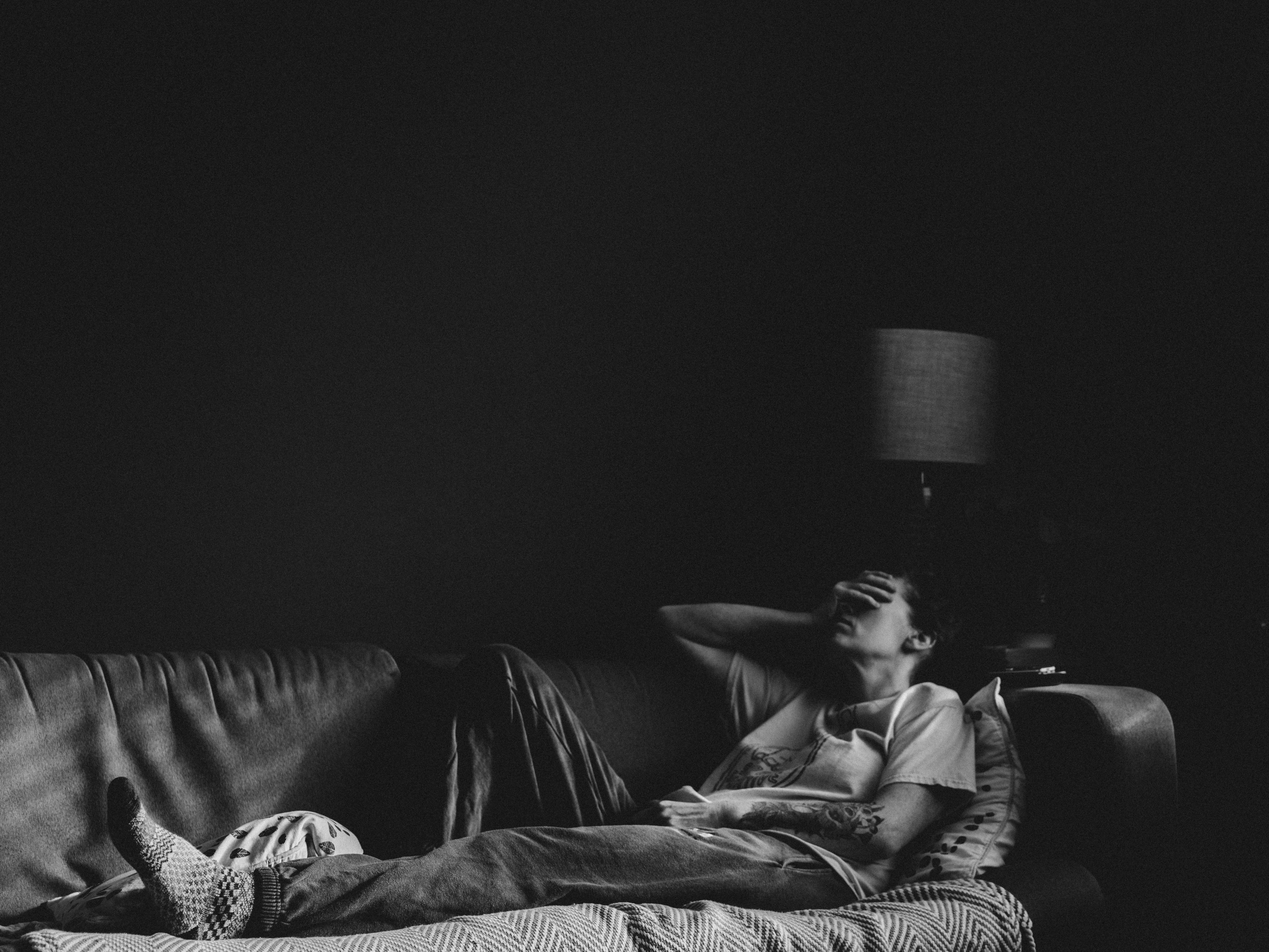 Lonely woman lying in a sofa A seemingly fatigued woman lying in a sofa in the living room