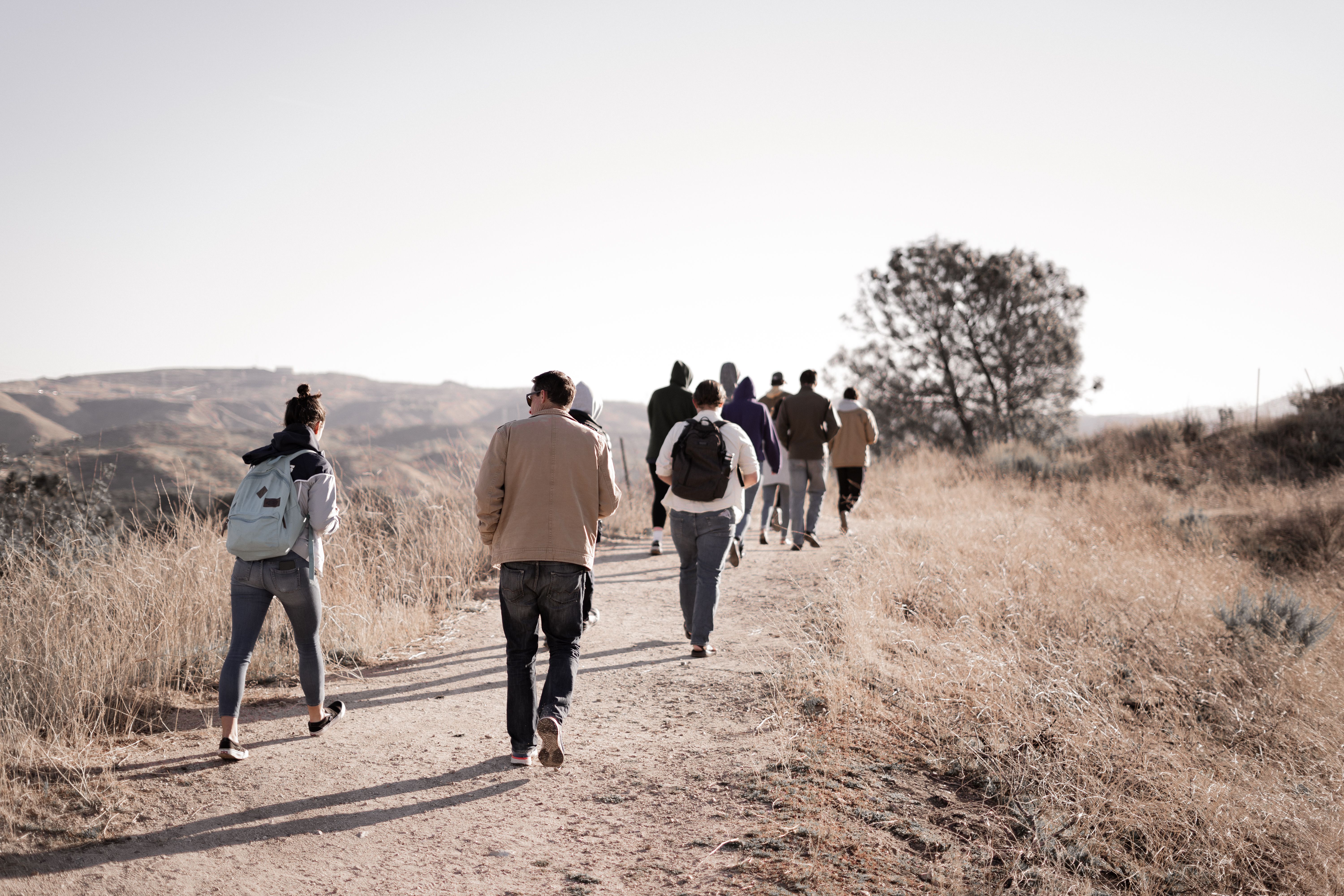 Group Hiking Adventure Through Arid Desert Trails Group of people walking along a dirt trail through dry grassland