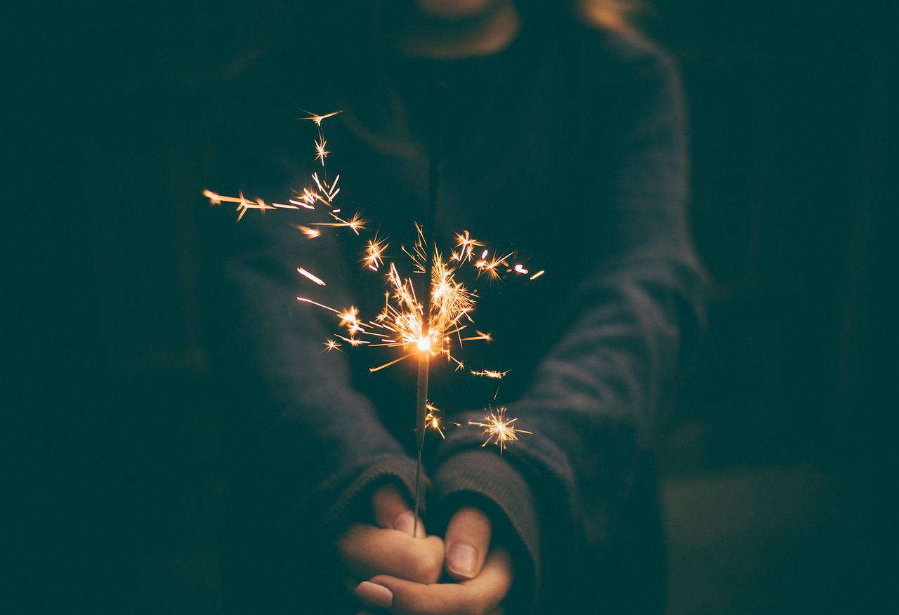 Festive sparkler moment for celebratory occasions Person holding a lit sparkler glowing brightly in the darkness